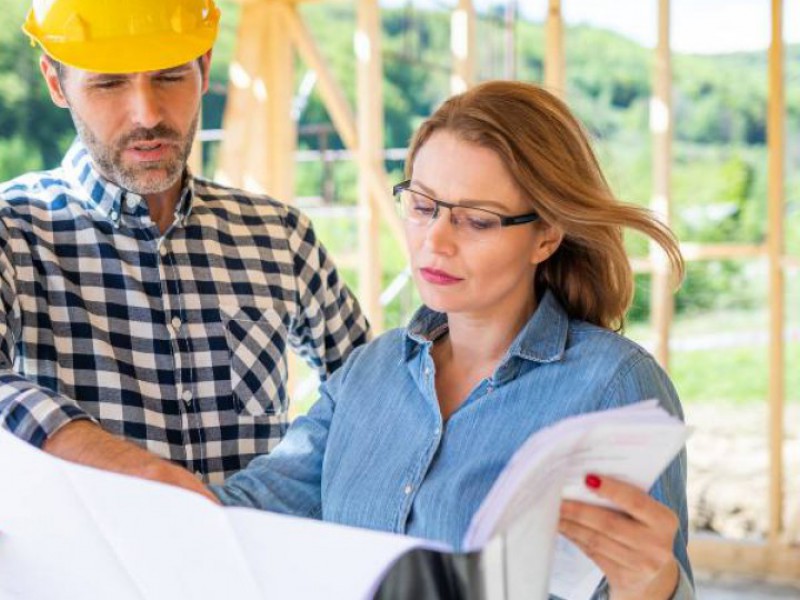 Propriétaire et chef de chantier examinant les plans d'une maison en construction