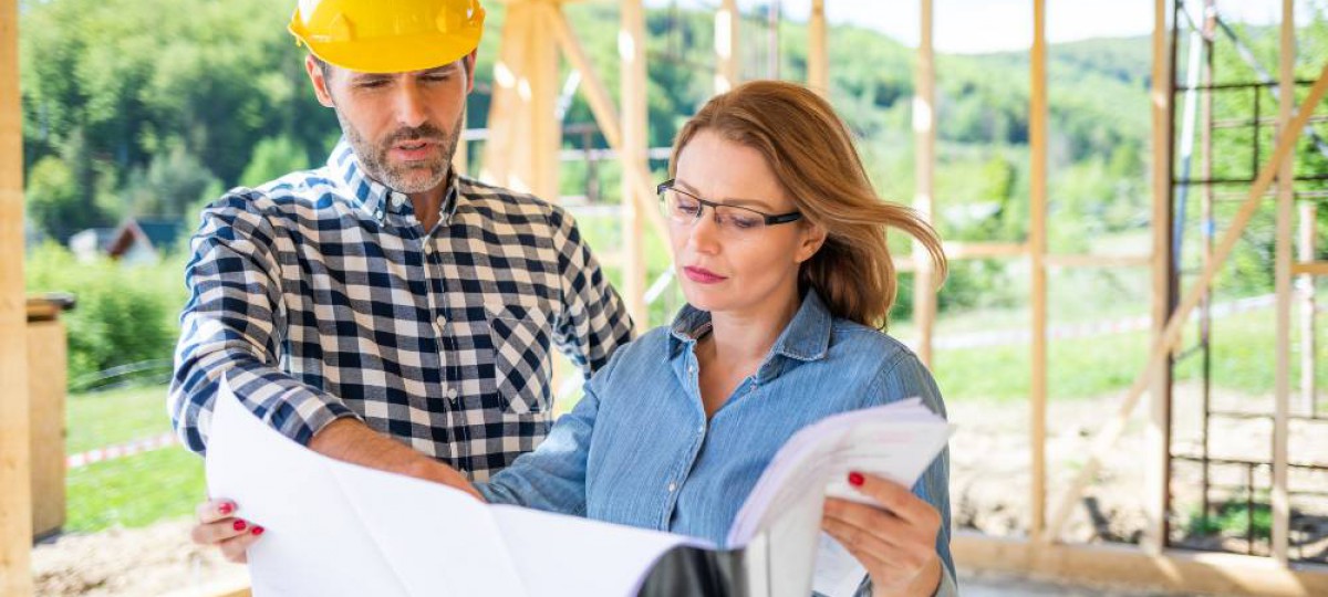 Propriétaire et chef de chantier examinant les plans d'une maison en construction