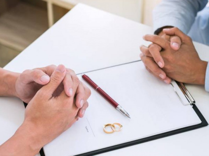 couple qui divorce devant des papiers à signer avec les alliances posées sur les papiers