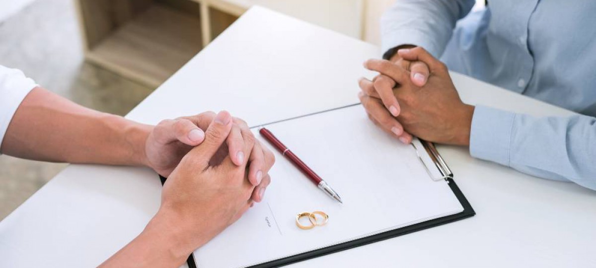 couple qui divorce devant des papiers à signer avec les alliances posées sur les papiers