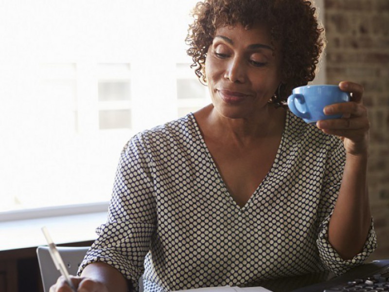 Une dame boit un café en attendant d'avoir une réponse à sa demande de rachat de crédits