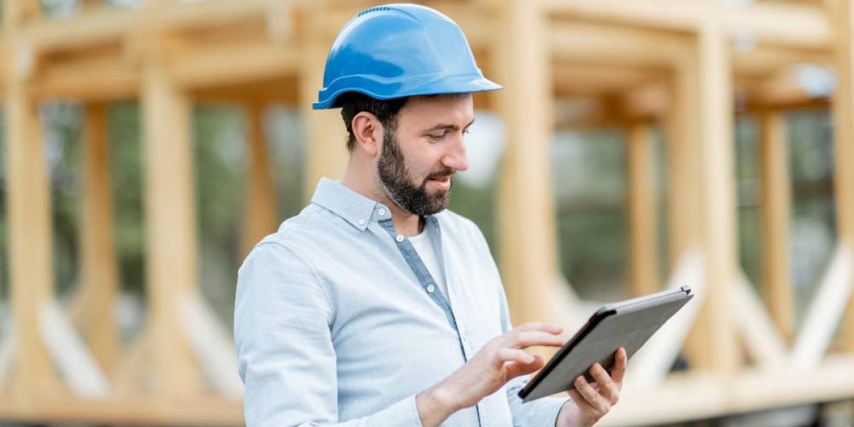 Homme tenant sa tablette numérique devant sa maison en cours de construction