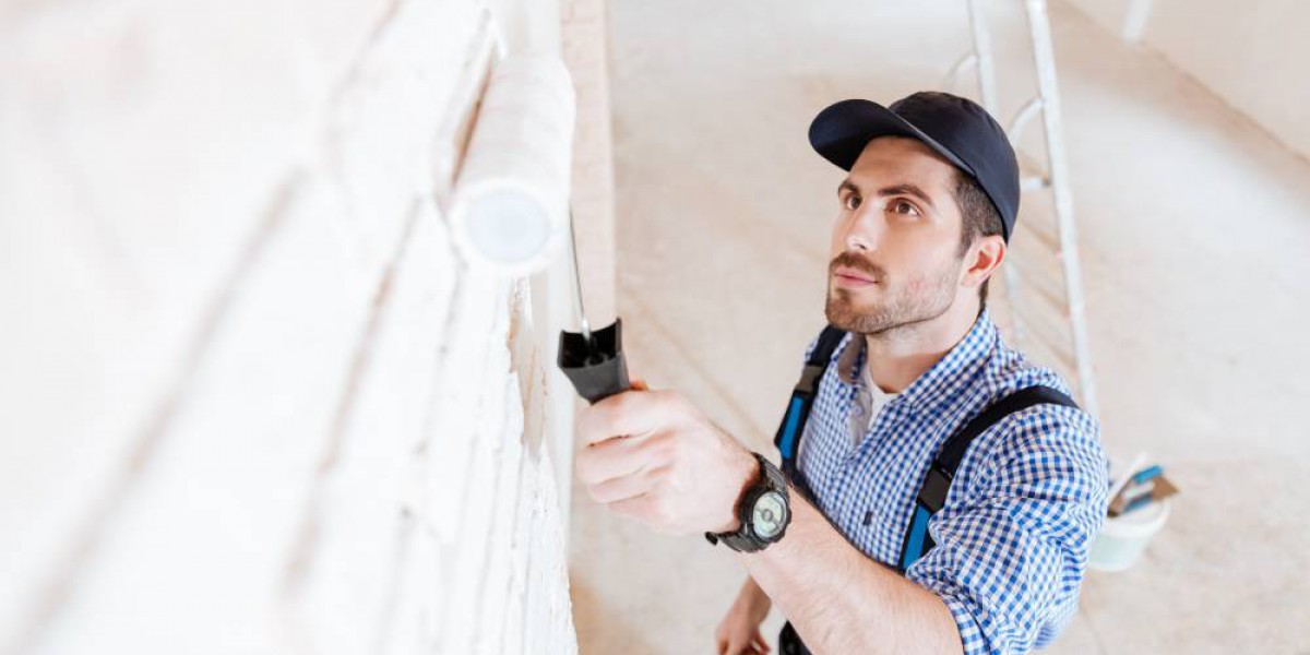 Homme peignant un mur en blanc après la pose d'une isolation et d'un revêtement décoratif