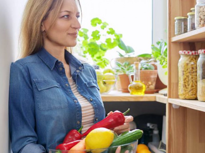 femme devant son étagère à bocaux avec légumes dans les bras