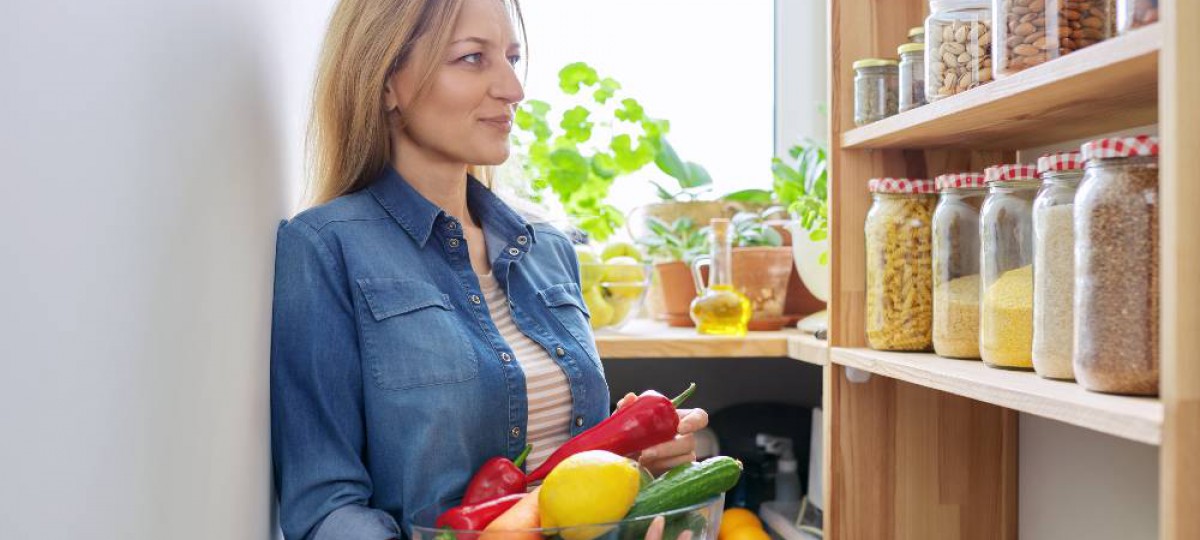 femme devant son étagère à bocaux avec légumes dans les bras