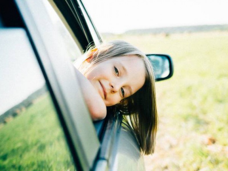 Petite fille passant la tête par la fenêtre d'une voiture dont la LOA a été regroupée avec un rachat de crédits