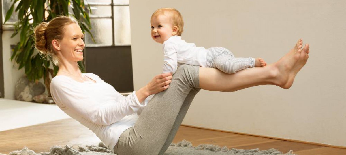 mère assise en équilibre au sol avec son bébé sur les jambes