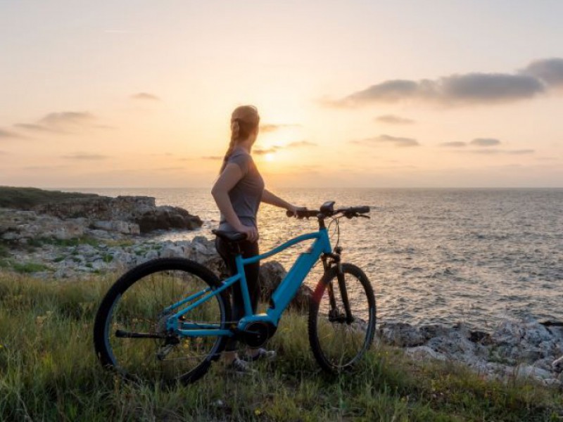 femme seule avec son velo eletrique admirant le paysage