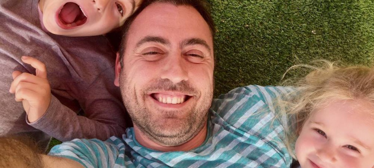selfie d'un papa et ses deux enfants allongés dans l'herbe