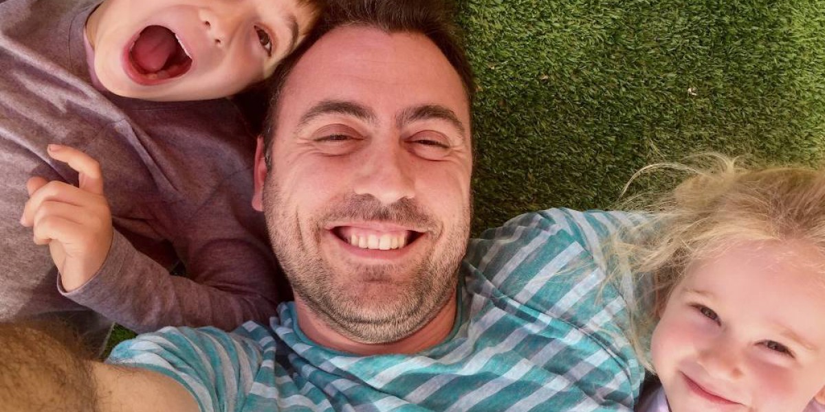 selfie d'un papa et ses deux enfants allongés dans l'herbe