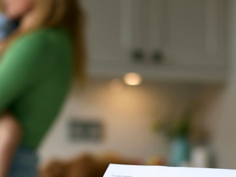 Une mère seule qui tient son enfant, avec une facture en premier plan