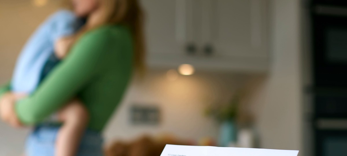 Une mère seule qui tient son enfant, avec une facture en premier plan