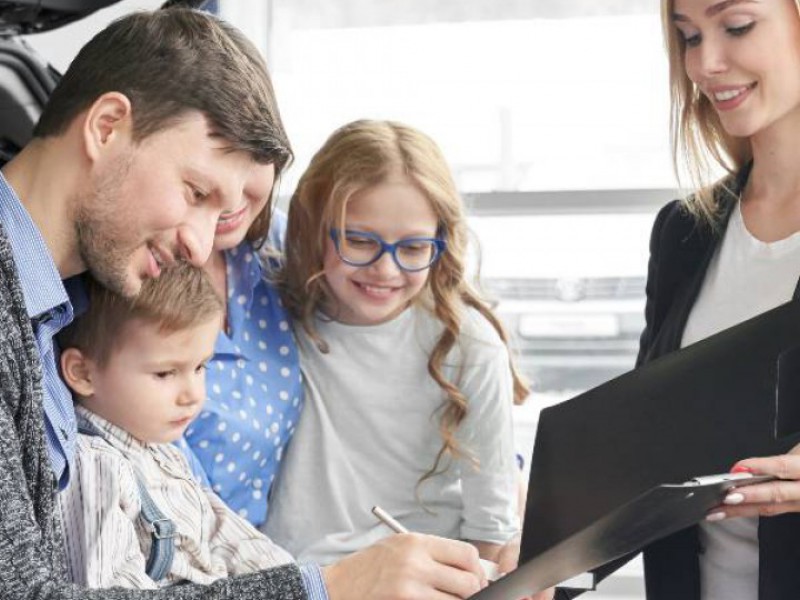 père célibataire, avec ses deux filles, signant l'achat d'une voiture avec la concessionnaire