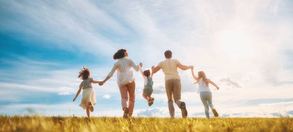 Famille heureuse courant dans un champs au soleil