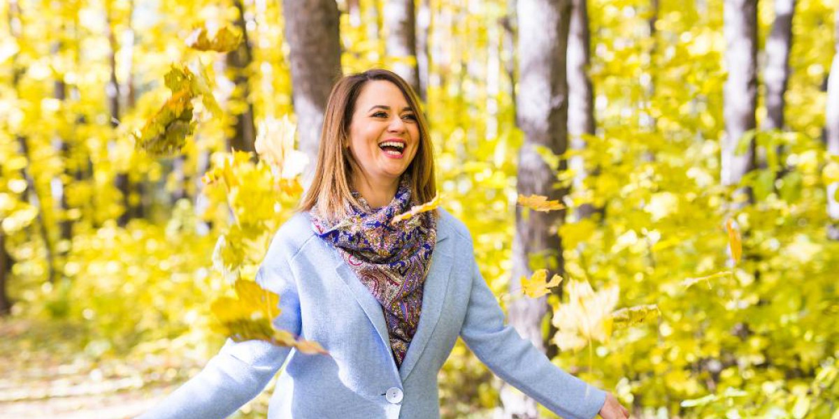 femme souriante laçant des feuilles dans un bois en automne