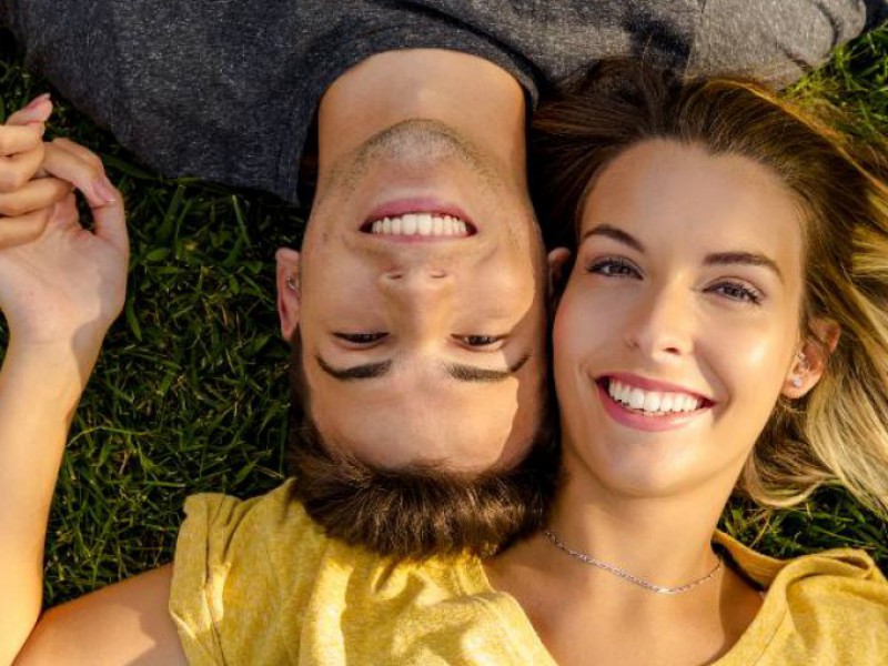 Couple heureux et souriant allongé dans l'herbe