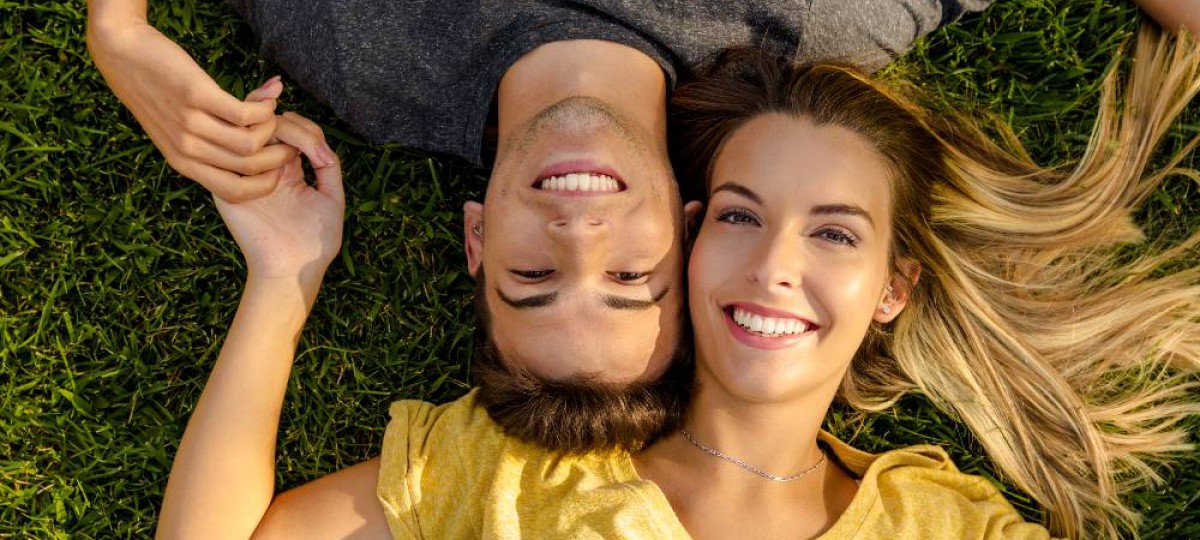 Couple heureux et souriant allongé dans l'herbe